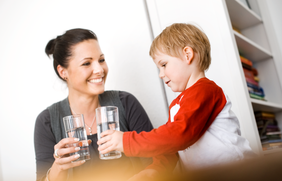 Mutter und Tochter mit Glas Trinkwasser