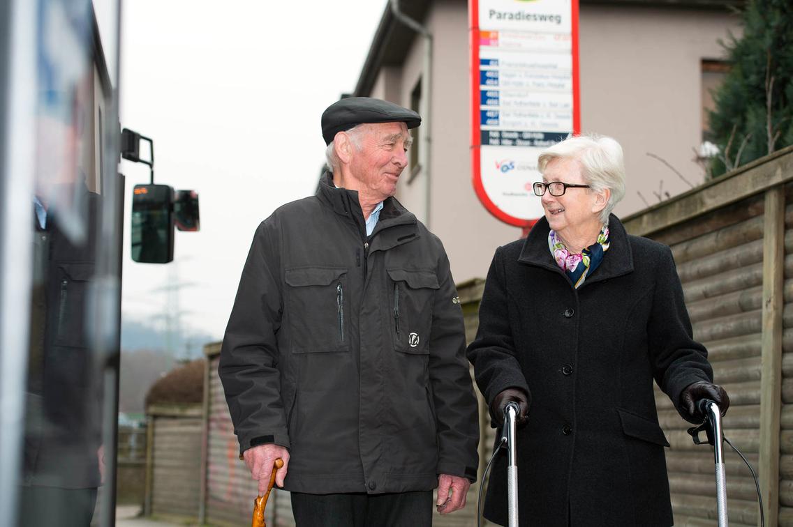 Älteres Paar steht an Bushaltestelle der VOS