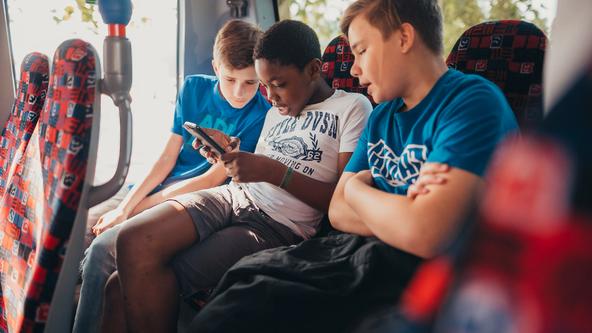 Drei Schüler sitzen nebeneinander im Bus