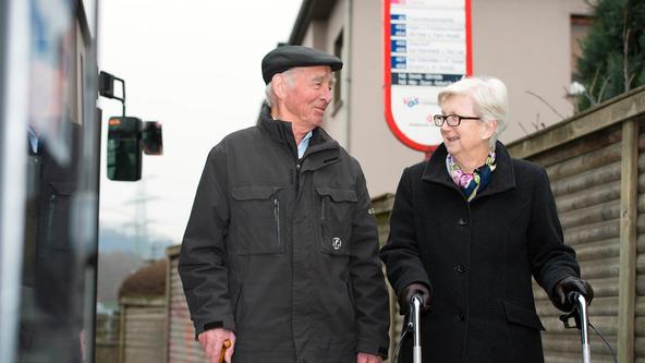 Älteres Paar steht an Bushaltestelle der VOS